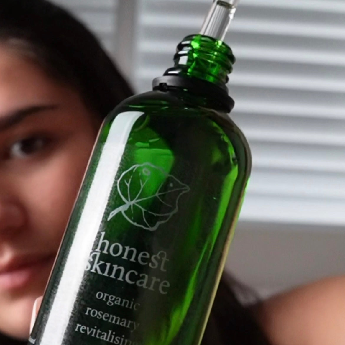 essential oils for hair health featuring a green bottle of organic rosemary revitalizing serum.