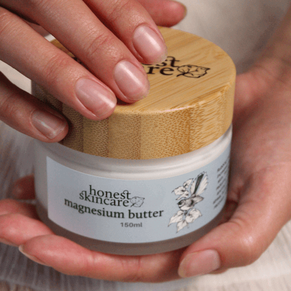 A person applying magnesium butter from a jar with a bamboo lid, promoting better sleep and relaxation.