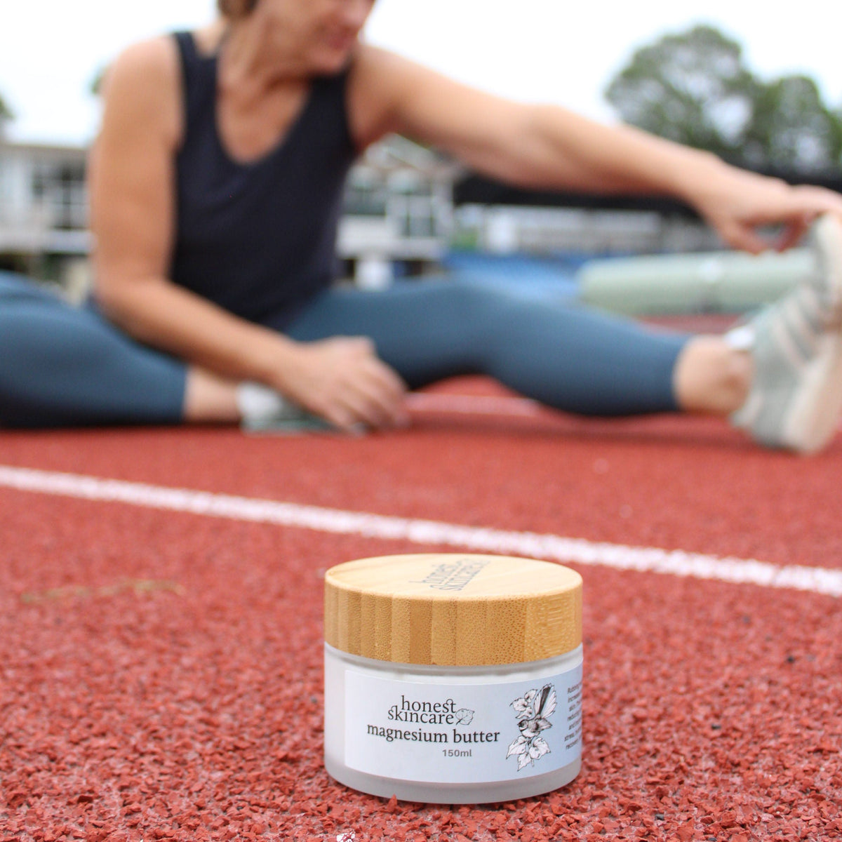 Magnesium butter product in focus for better sleep, while a woman stretches on an athletic track.