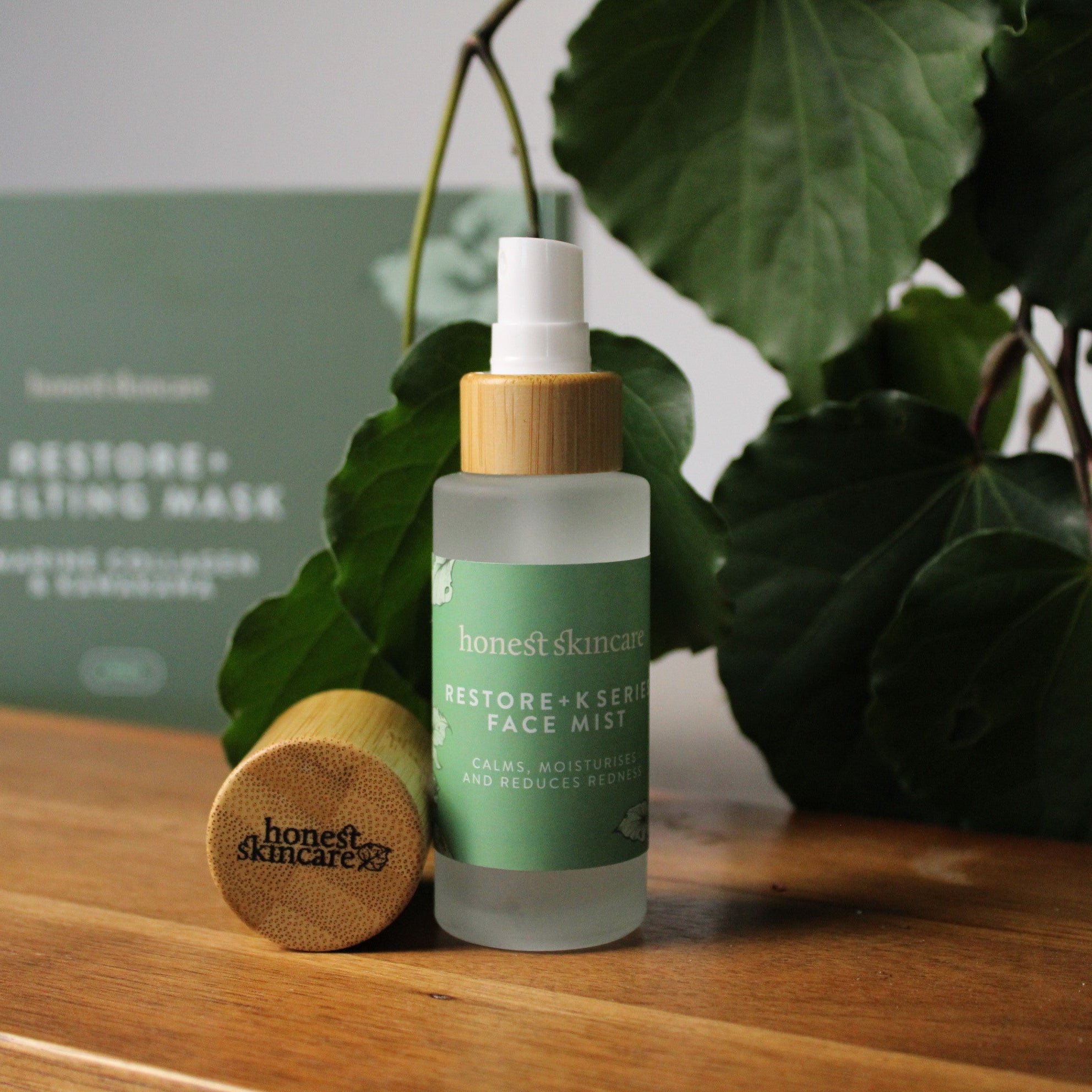 Restore+ Kawakawa & Manuka Face Mist in a bottle with bamboo cap placed on wood with kawakawa.