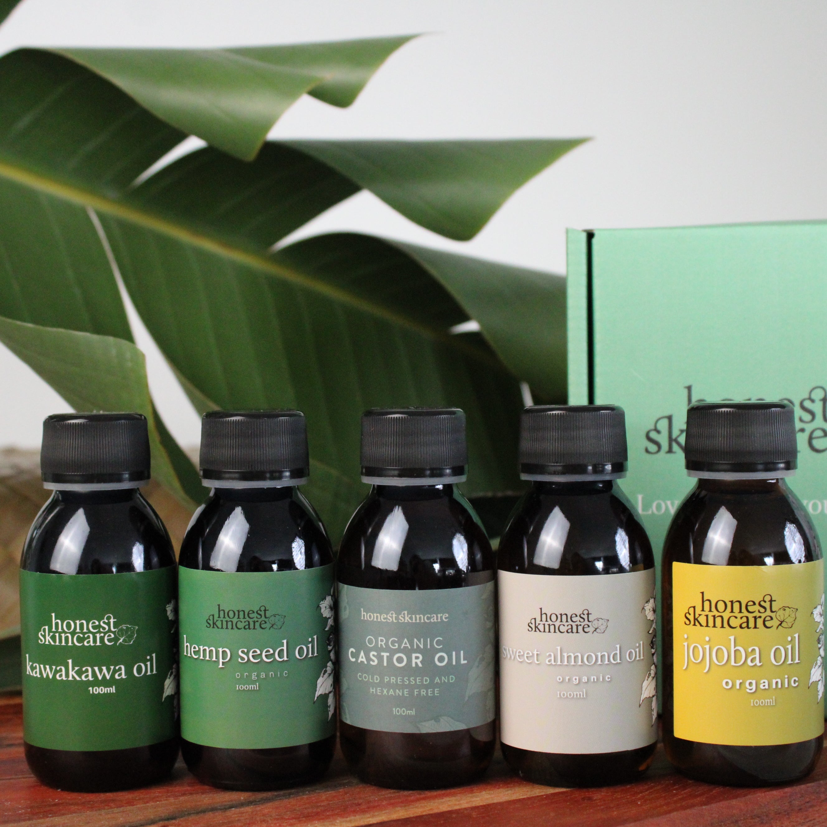 Set of five bottles of Organic oil sampler set - honest skincare s on a wooden surface with a green box in the background.