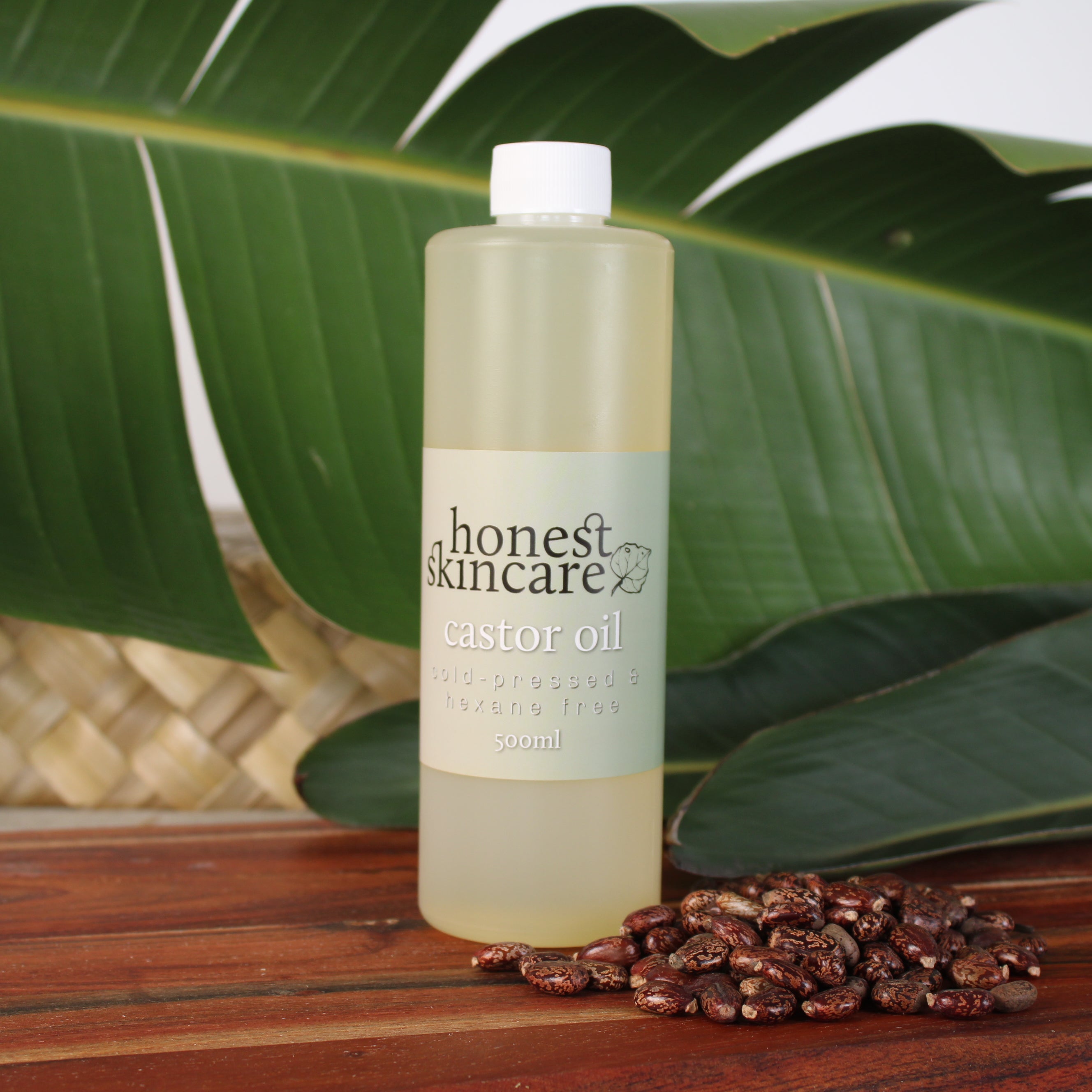 Bottle of 'honest skincare' castor oil on a wooden surface with leaves in the background