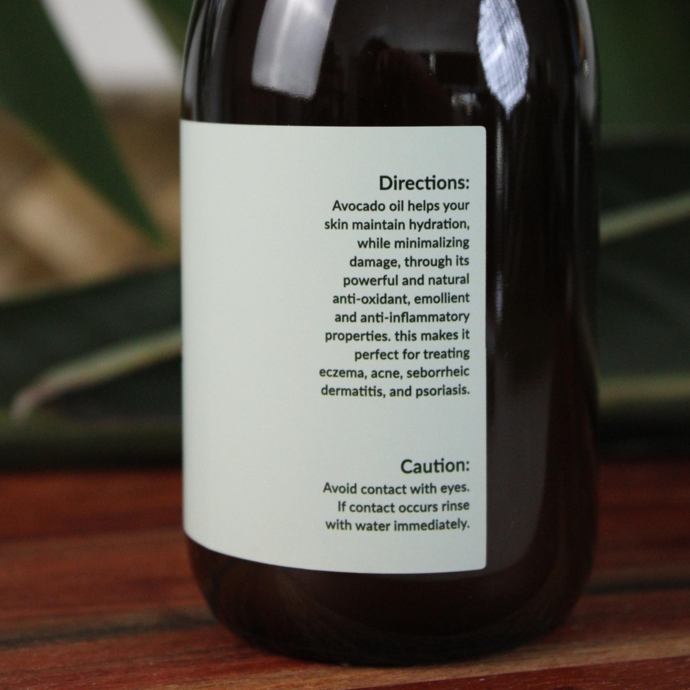 Bottle of honest skincare organic avocado oil with a label on a wooden surface