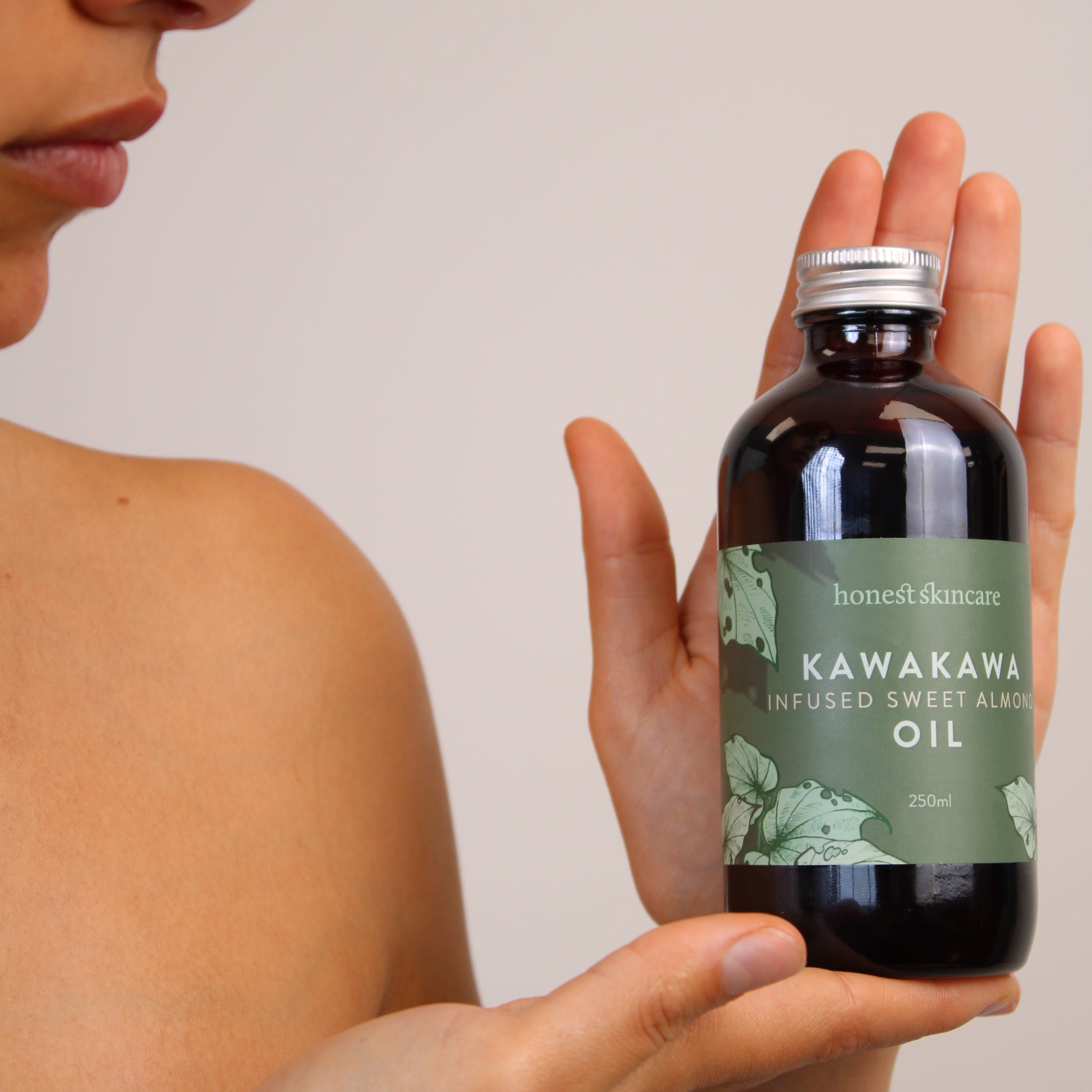 Person holding a bottle of Kawakawa oil with a neutral background