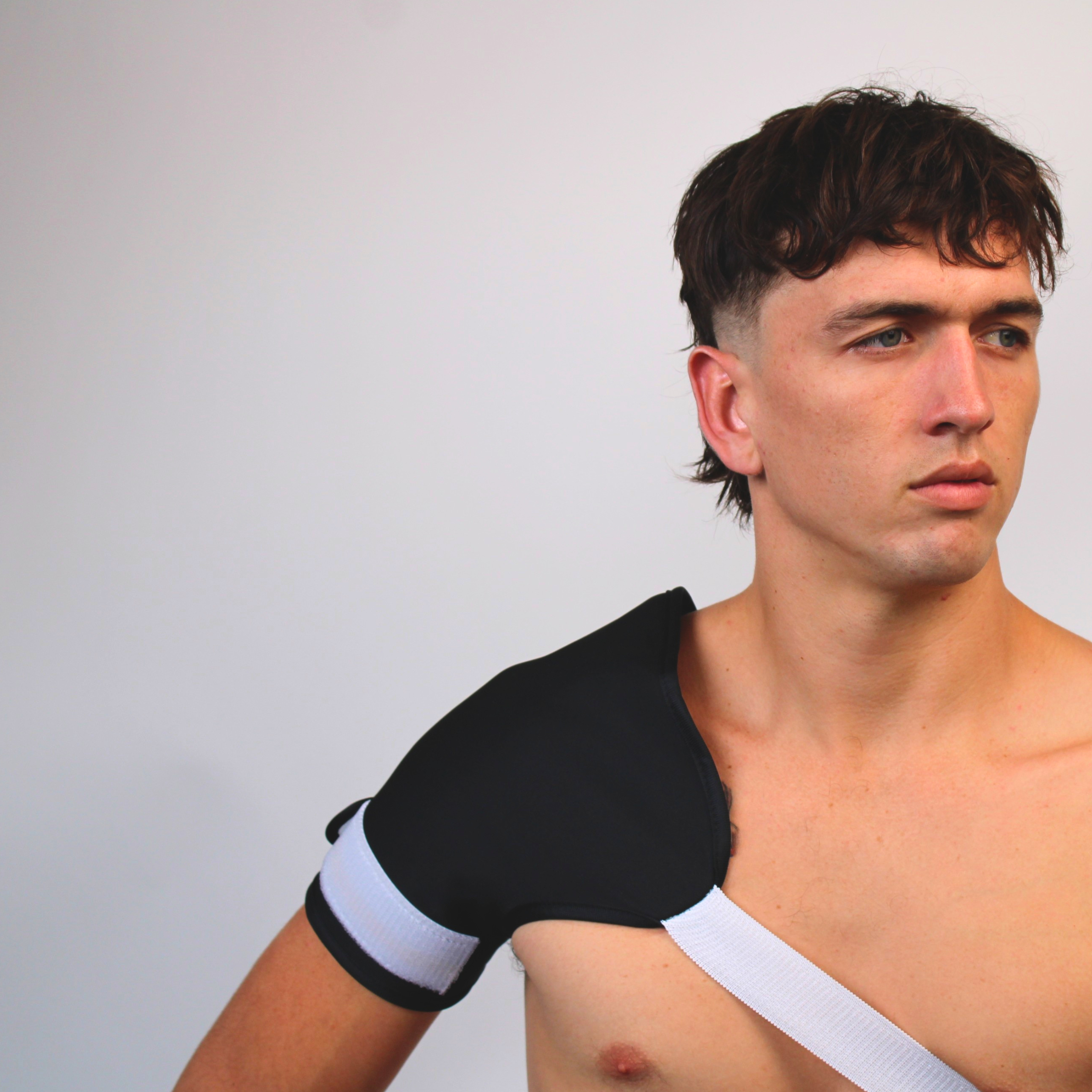 Man wearing a castor oil shoulder wrap against a plain background
