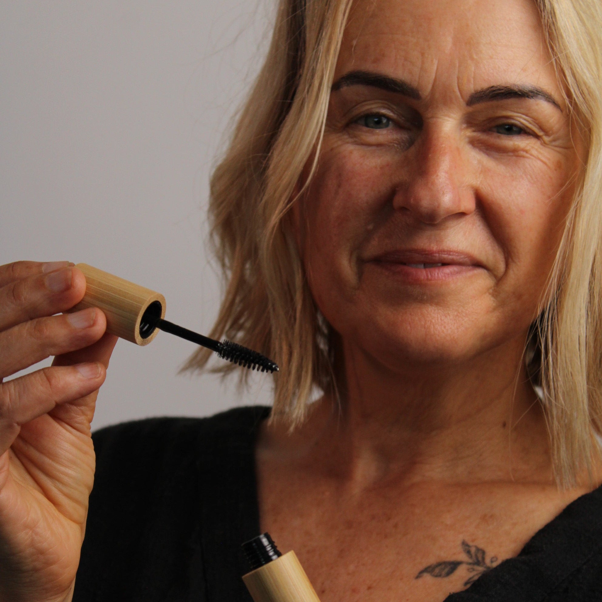 Person holding two bamboo organic castor oil mascara tubes with a neutral background