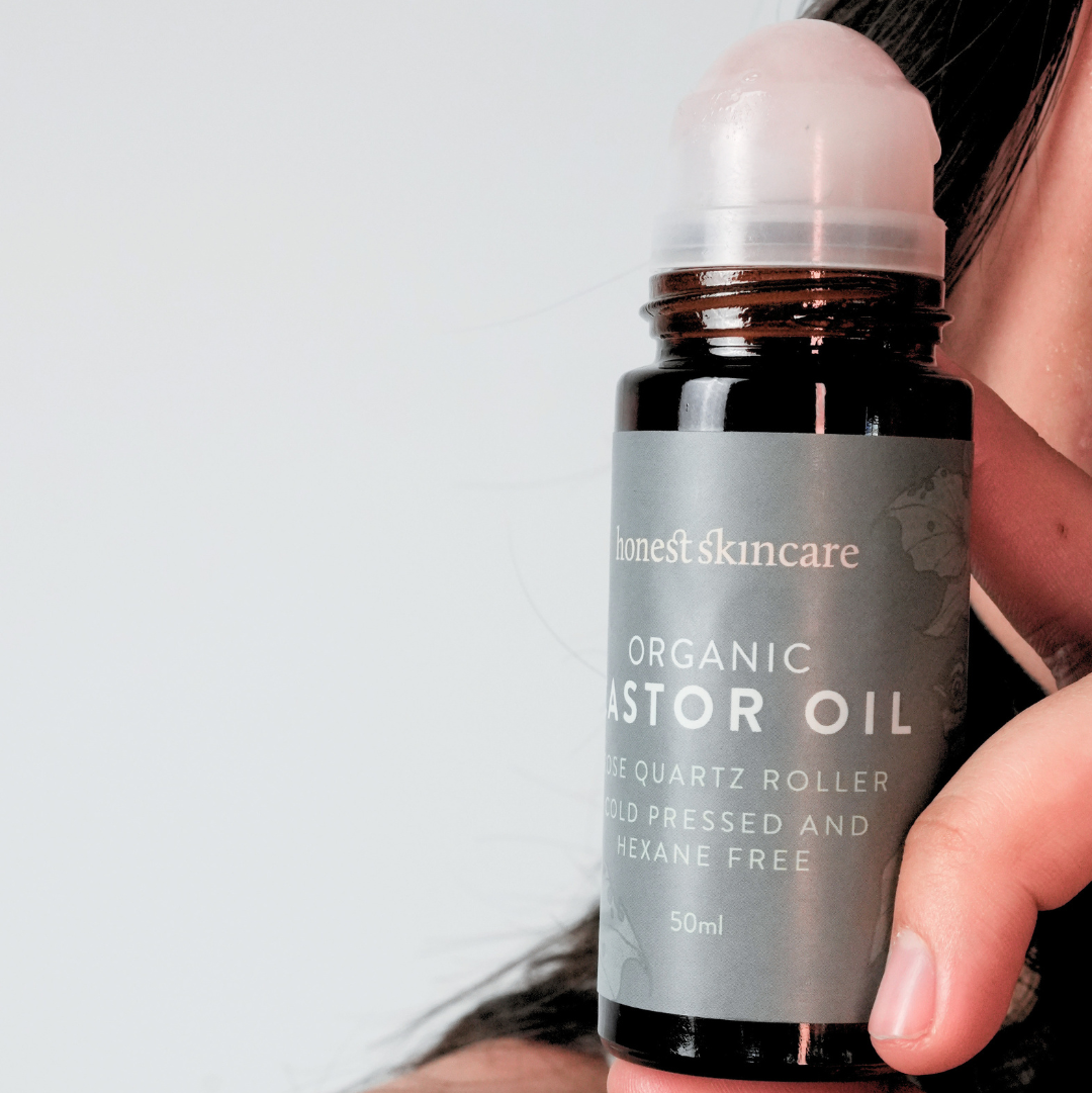 Hand holding a bottle of 'Organic Castor Oil' by 'unonest skincare' against a white background.