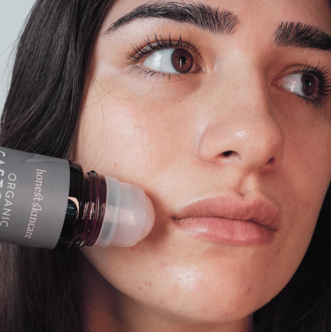 Woman applying a skincare product to her face with 'honest skincare' bottle visible.