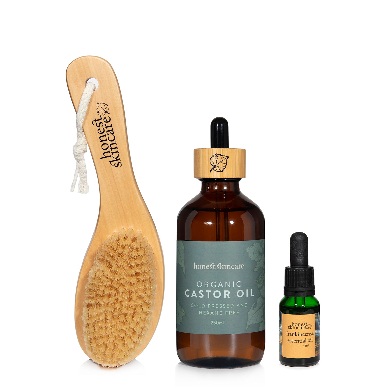 Wooden brush and bottles of organic castor oil and frankincense essential oil on a white background