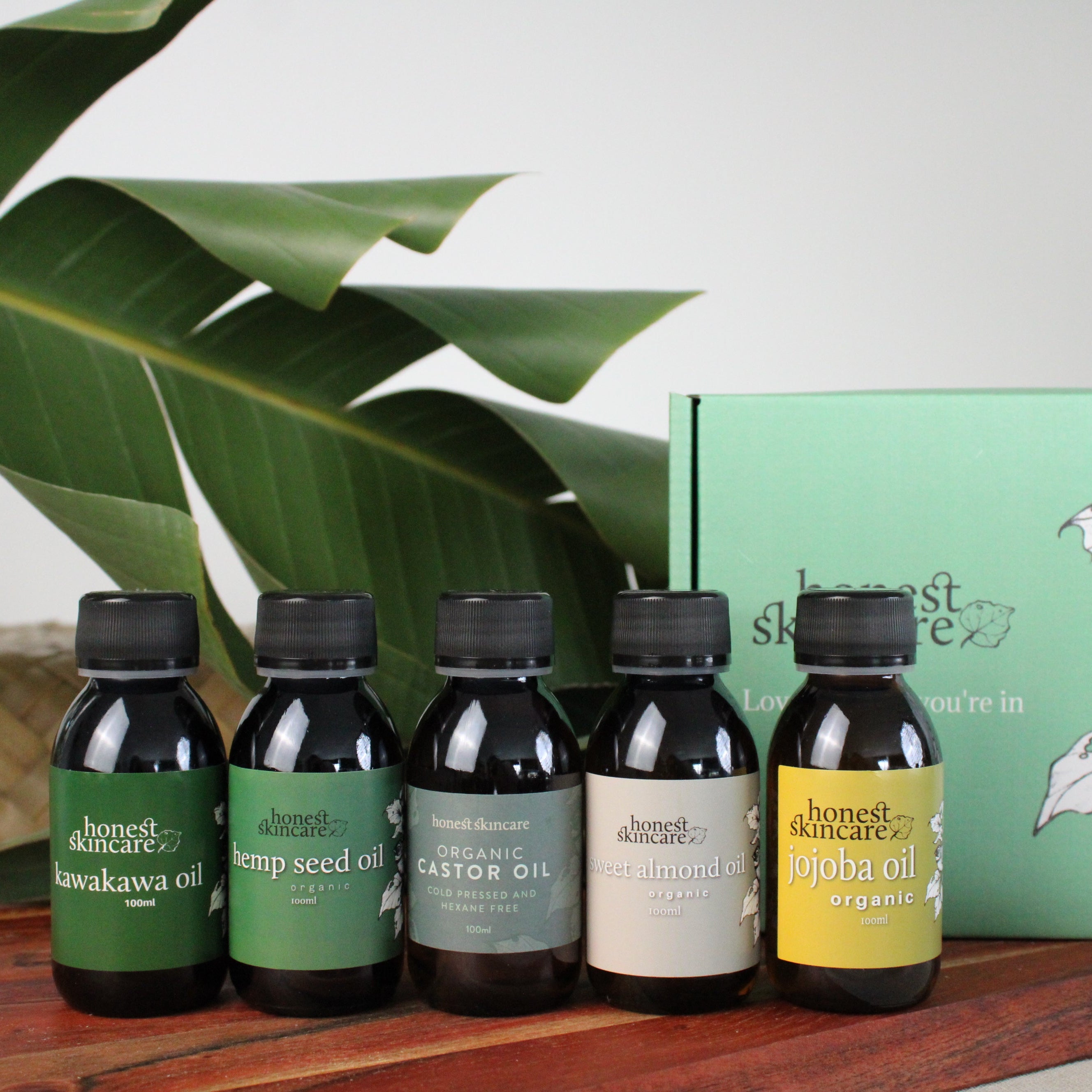 Organic oil sampler set - honest skincare  with labels on a wooden tray next to a green box with branding.