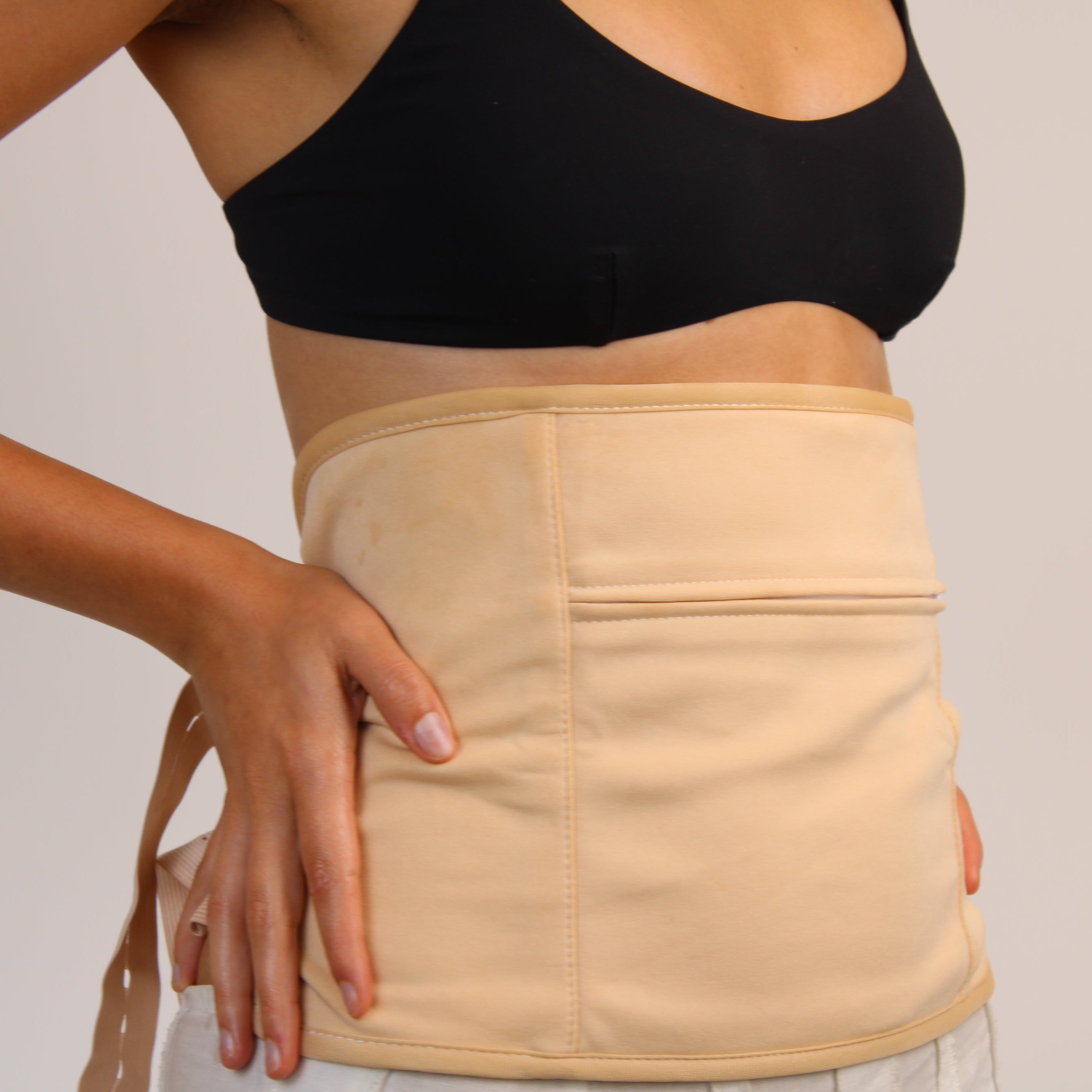 Person wearing a beige waist trainer against a plain background coco