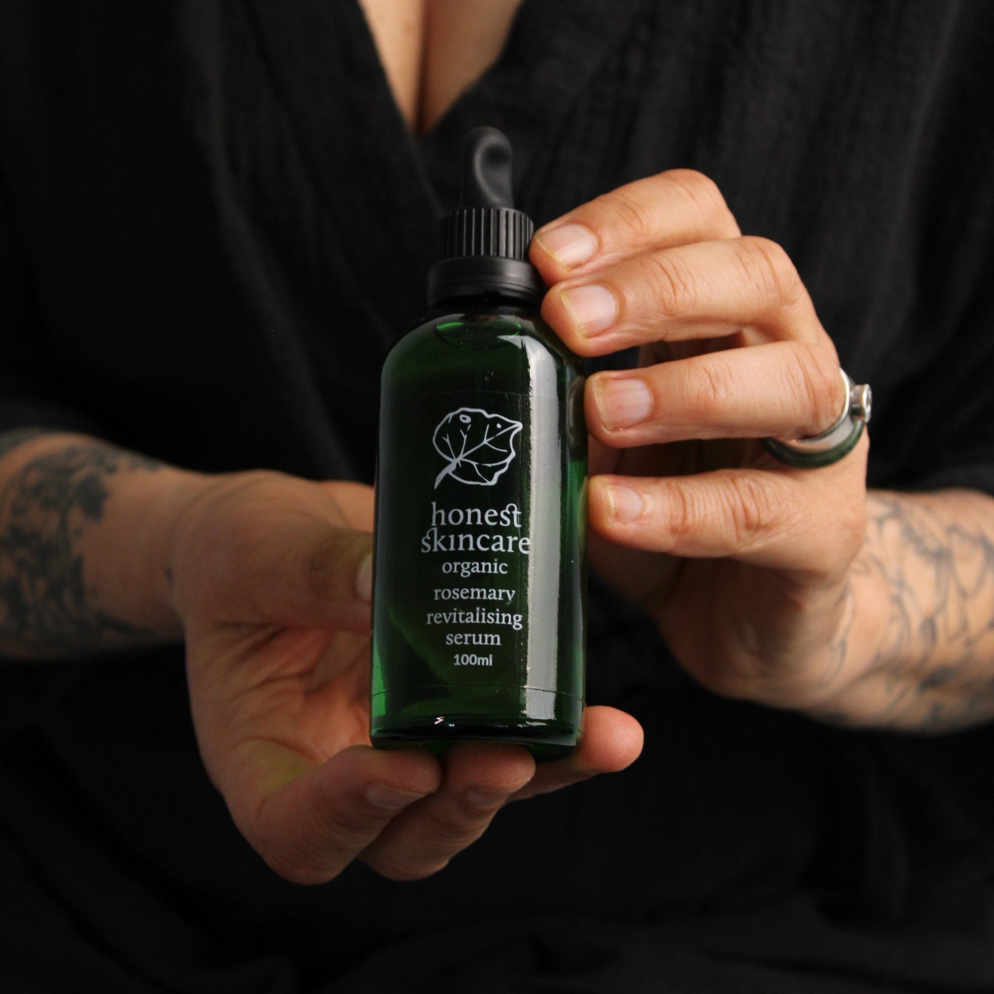 Person holding a revitalising Rosemary with a brand logo against a dark background