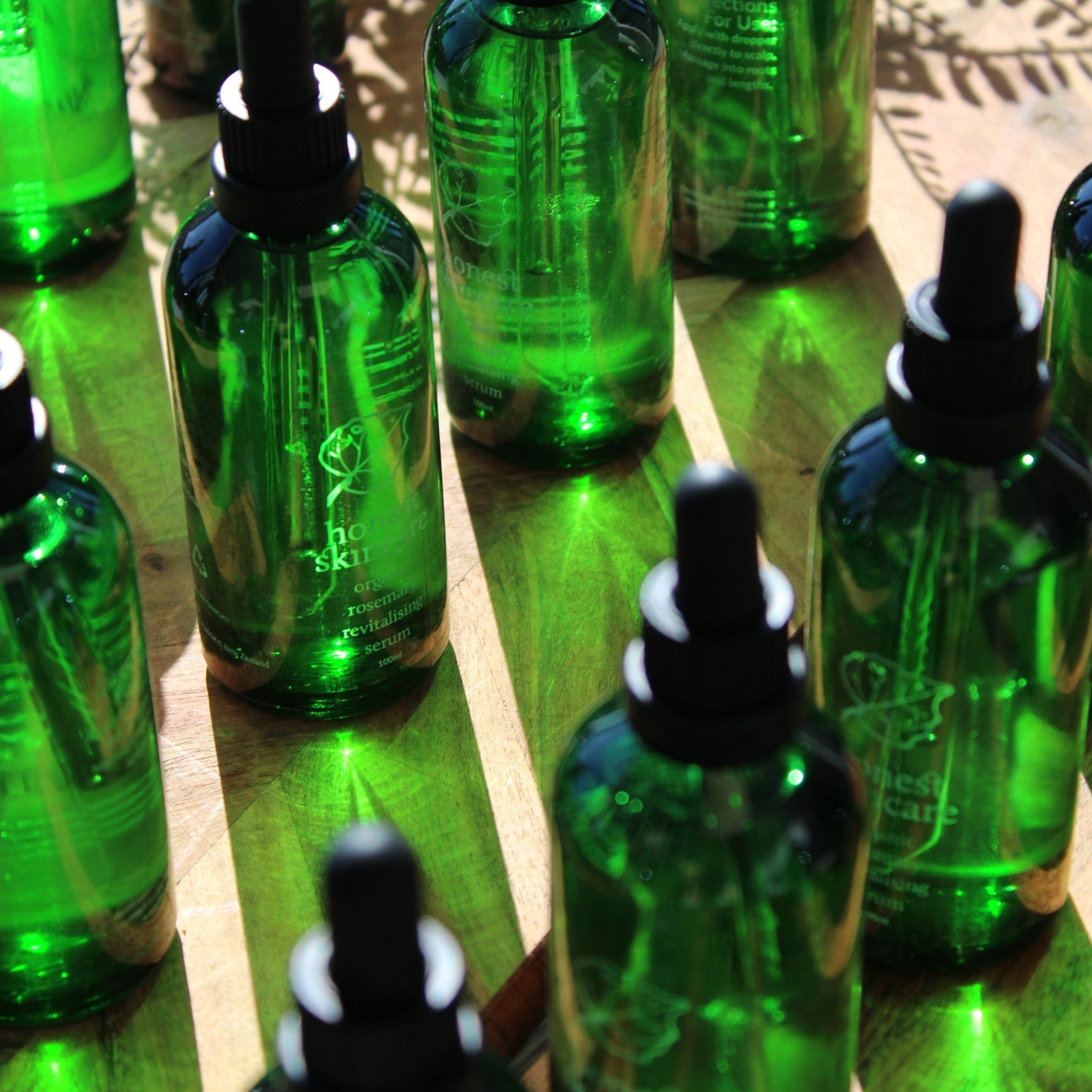 Stack of green bottles with black caps on a reflective surface