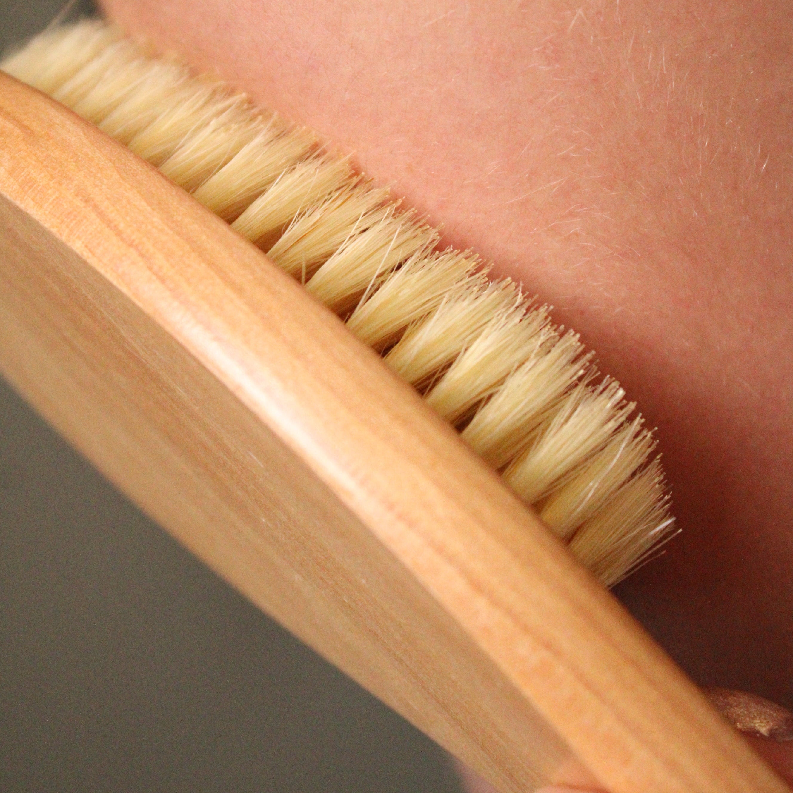 Wooden brush with bristles being used on a person's skin