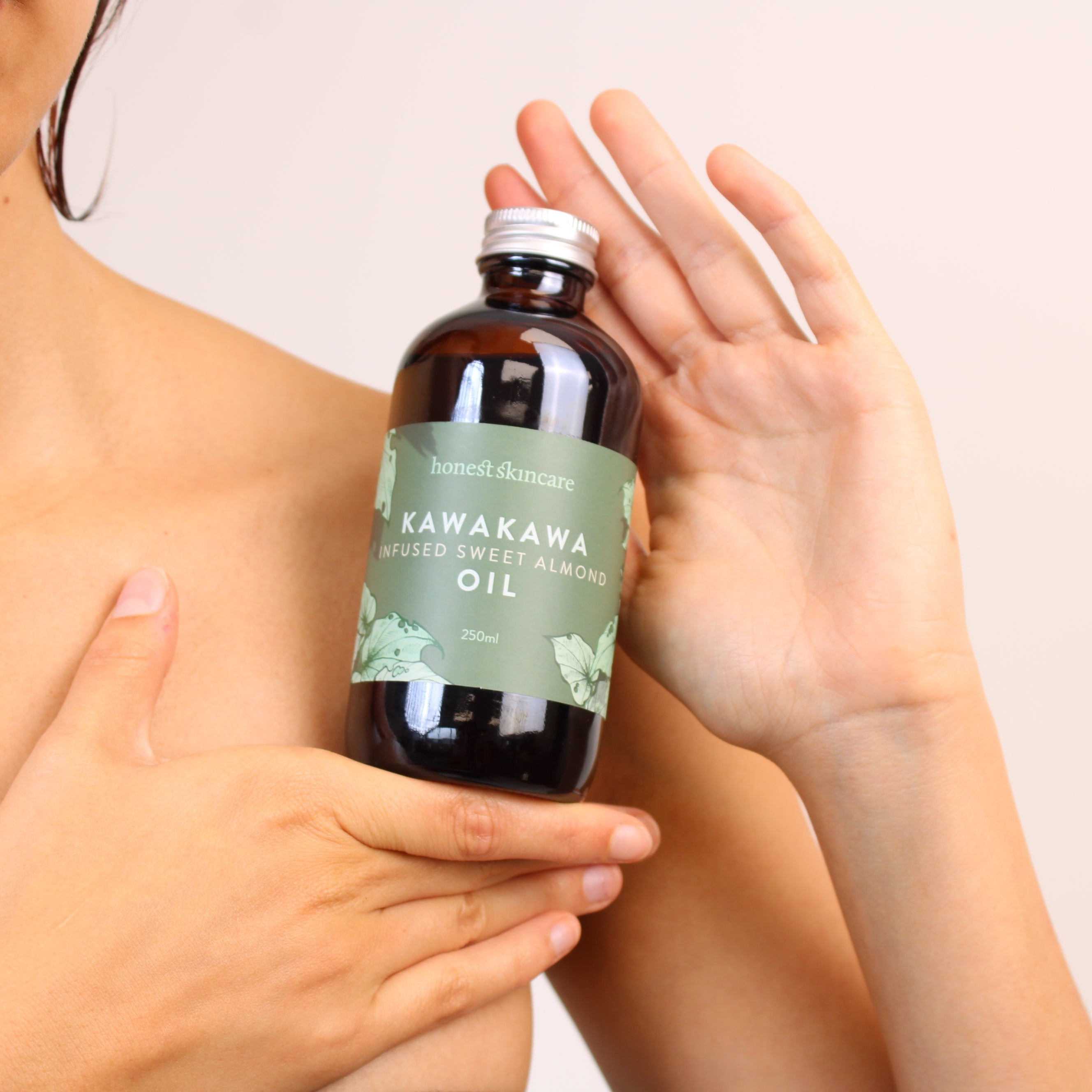 Person holding a bottle of Kawakawa oil with a beige background