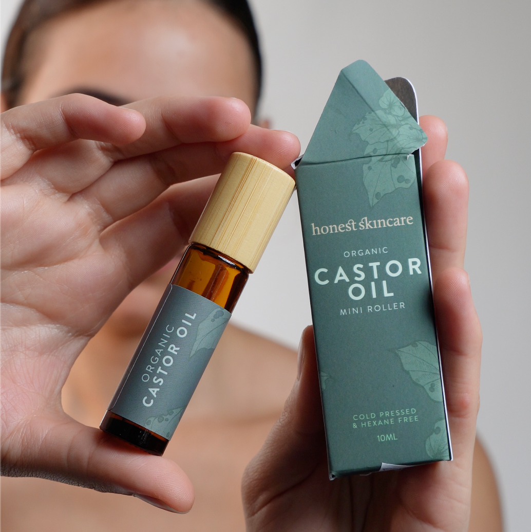 Person holding a bottle and box of honest skincare Castor Oil