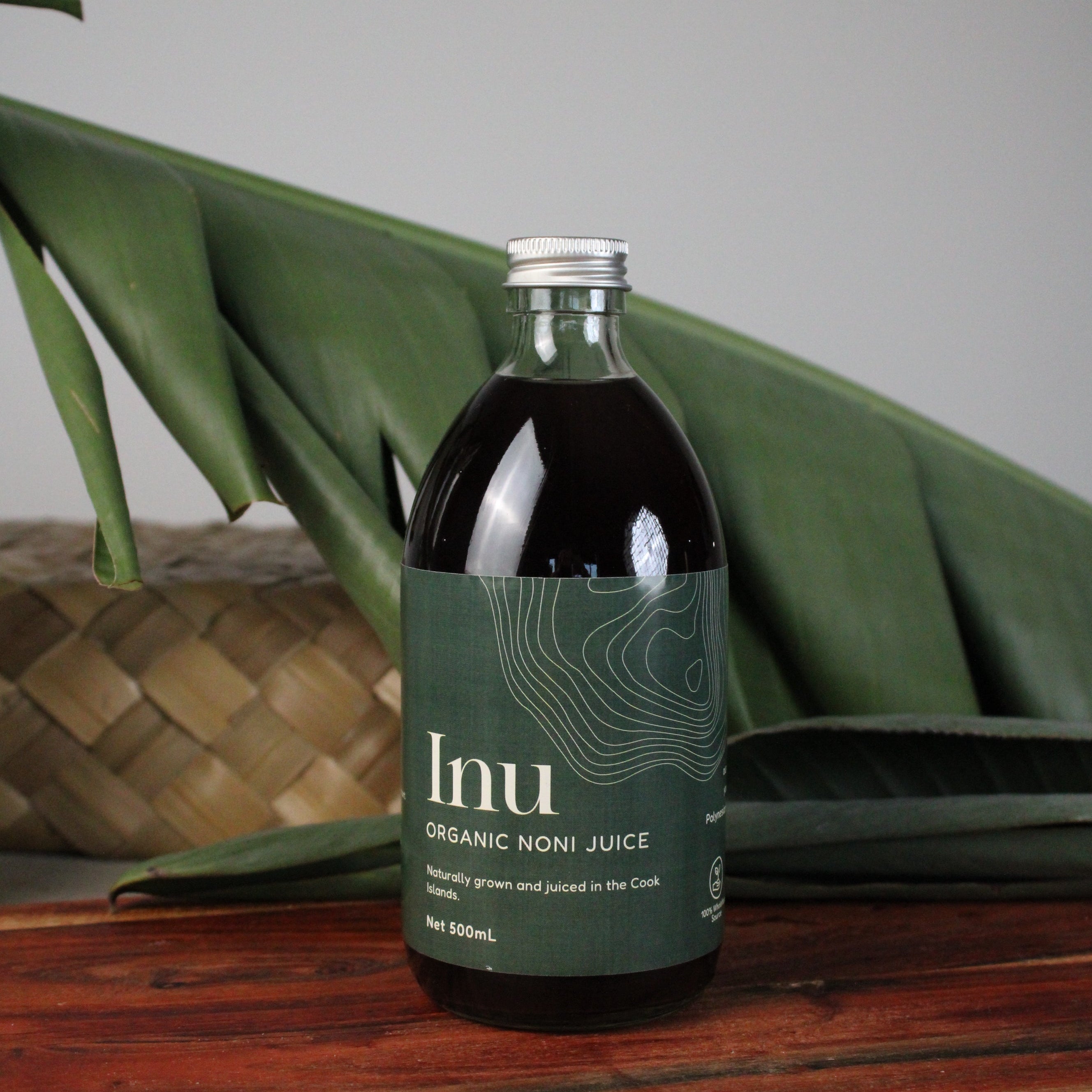 Bottle of noni juice with a green label on a leafy background